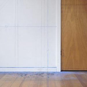 Documentation of drawing installation that used black pencil and blue chalk stringlines to trace the timber structure of a room in a suburban house. Detail view of floor, cupboard and shirting board.
